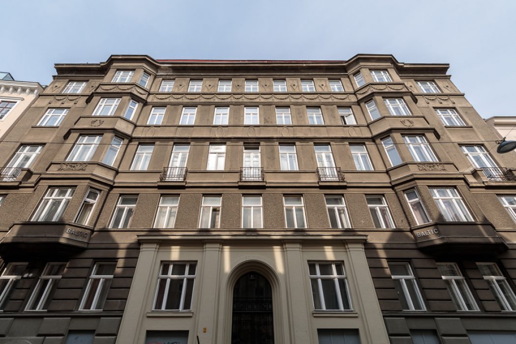 Fassade eines historischen, mehrstöckigen Gebäudes mit zahlreichen Fenstern und einem großen Torbogen, Beschriftung "BALTIC" sichtbar.